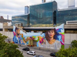 A giant mural of a man and a woman with colorful designs in the background, in New York City