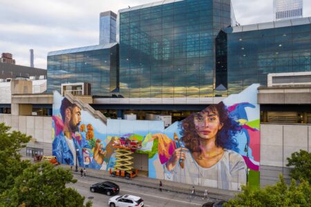 A giant mural of a man and a woman with colorful designs in the background, in New York City