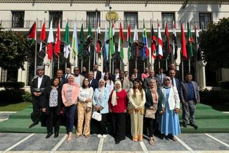 Participants at the Biosaline Agriculture as an approach to land restoration in the Arab world, in Cairo, Egypt, pose in front of flags