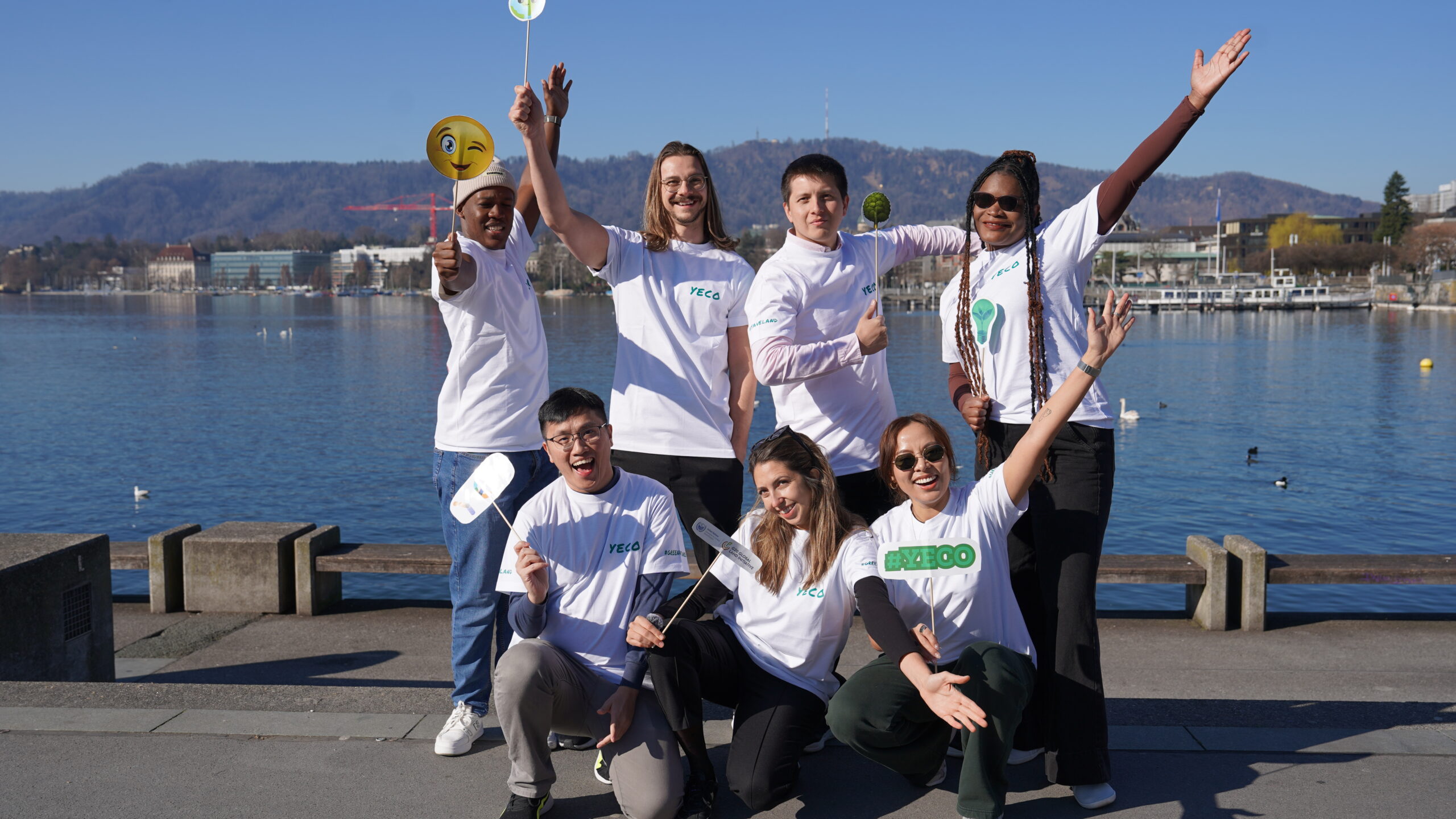 Group of young men and women holding signs and raising hands by Lake Zurich in Switzerland