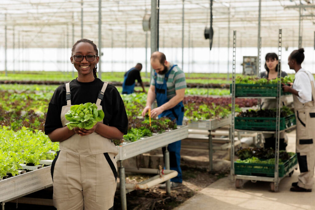 A young woman holds a lettuce in a greenhouse