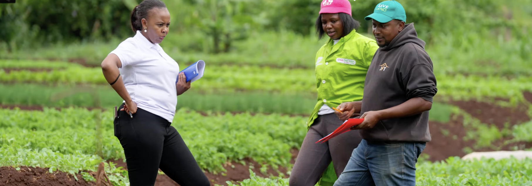 Three people converse in fields in Kenya