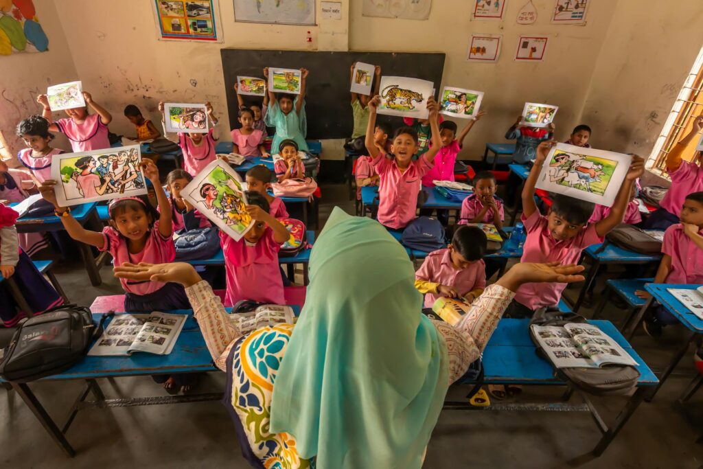 Students hold up signs in front of a teacher in Bangladesh