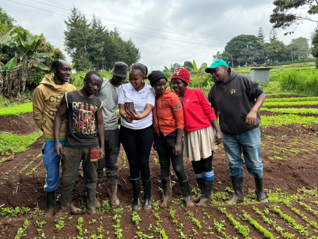 Maryanne Gichanga showing on her phone to farmers