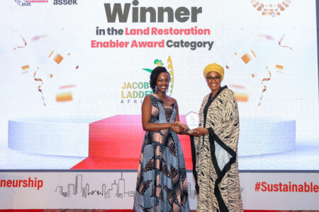 A woman hands an award to another woman at an event, in Kenya